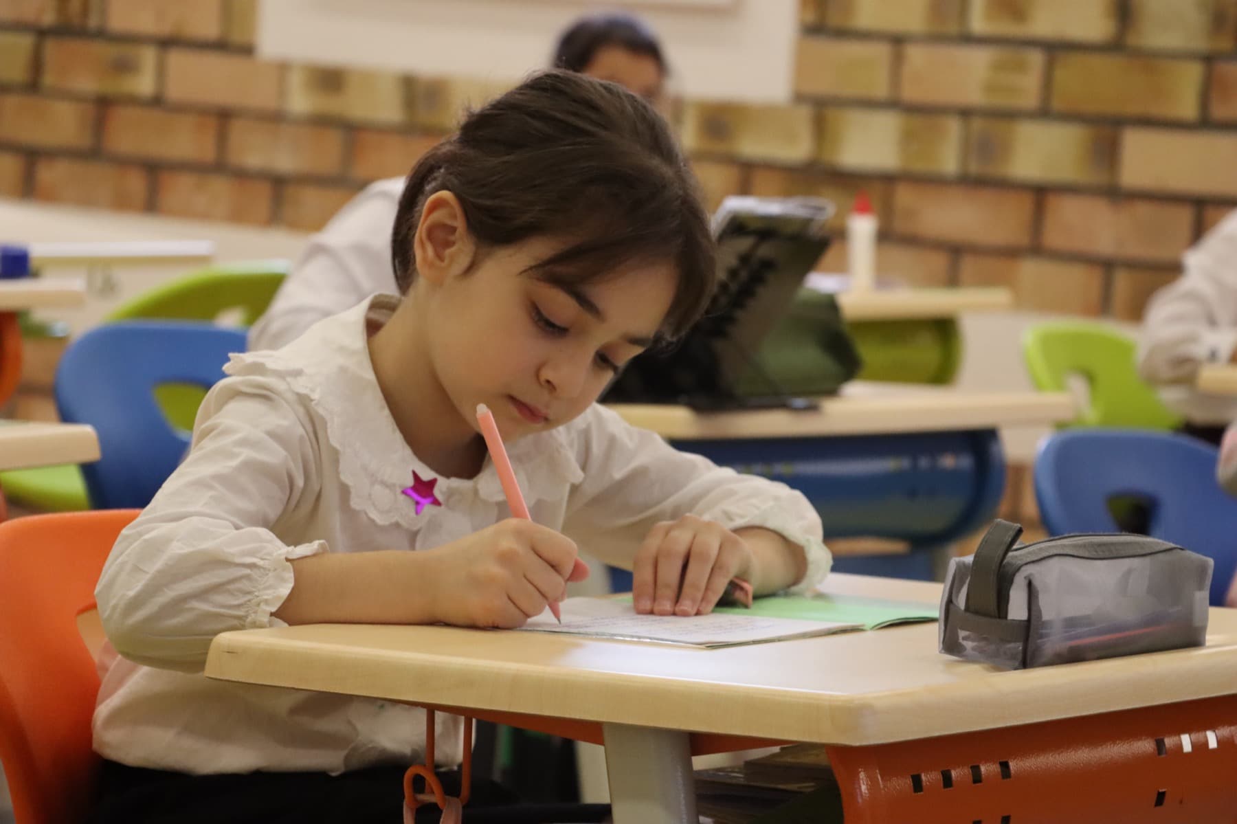 A primary pupil at work in her exercise book